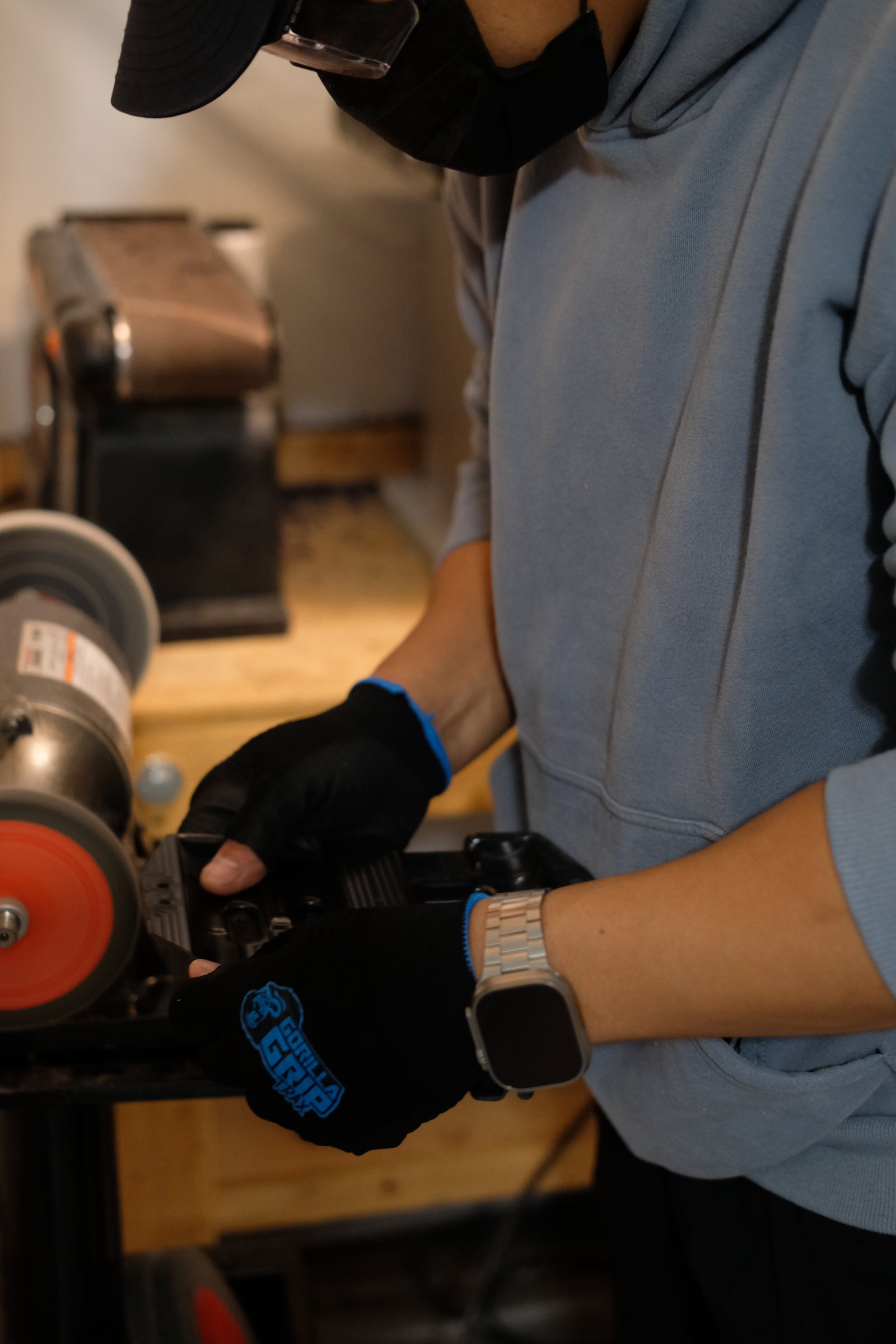 Holster maker shaping a Kydex component on the bench grinder at the TUKD workshop in Las Vegas